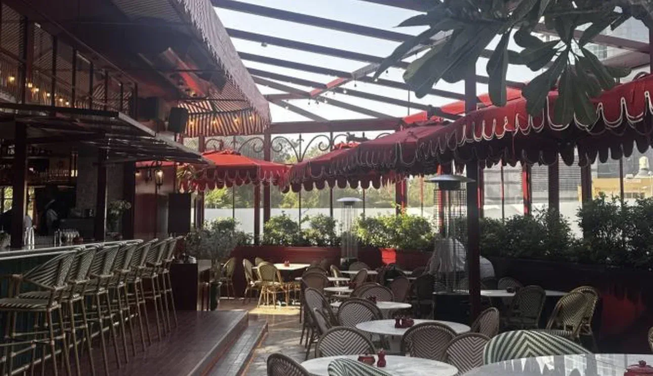 Open-air restaurant terrace with red awnings and green chairs in Dubai.